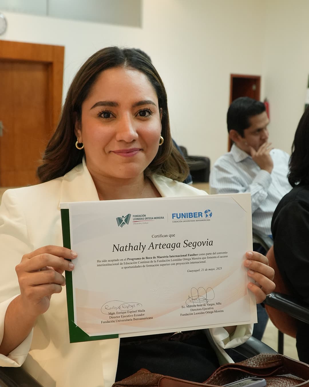 Becaria mostrando su certificado de maestría